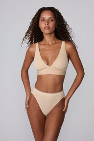 In a studio setting, Courtney wears the Smooth Seamless Brief in Beige with the matching Smooth Seamless Bralette in Beige. The front view highlights the high-leg silhouette, smooth waistband, and comfortable coverage.
