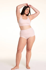 On a light studio backdrop, Alessandra wears the Bliss Boyshort in Ember Rose with the matching bra. The full-body image highlights the mid-rise waist, full-coverage silhouette, smooth fabric, and coordinated set. sizing: Alessandra wears size Large