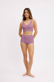 In a studio setting, Darion wears the Bliss Bralette in Mirage with matching underwear, shown in a full-body view. The bralette features a scoop neckline, wireless construction, and a wide underband for everyday comfort.