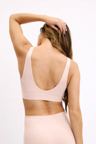 On a light studio backdrop, Darion wears the Bliss Bralette in Rose, shown from the back. The bralette features a scoop back, wide straps, and a smooth underband.