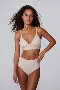 In a studio setting, Courtney wears the Bliss Highwaist Brief in Pebble with a matching bra. A front-facing view highlights the smooth fabric, high-rise waistband, and full-coverage silhouette.