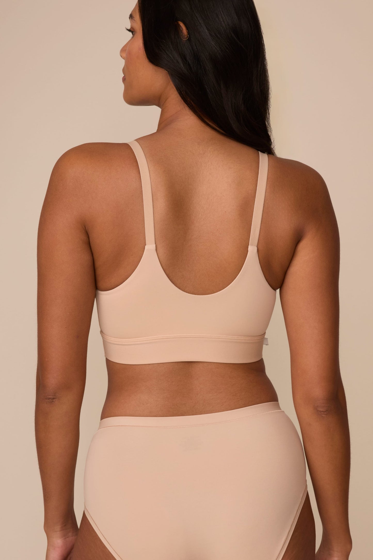 On a neutral studio backdrop, Victoria wears the Bliss Nursing Bralette in Beige with matching underwear. The back view showcases the smooth back panel, adjustable straps, and wide underband for comfortable support.