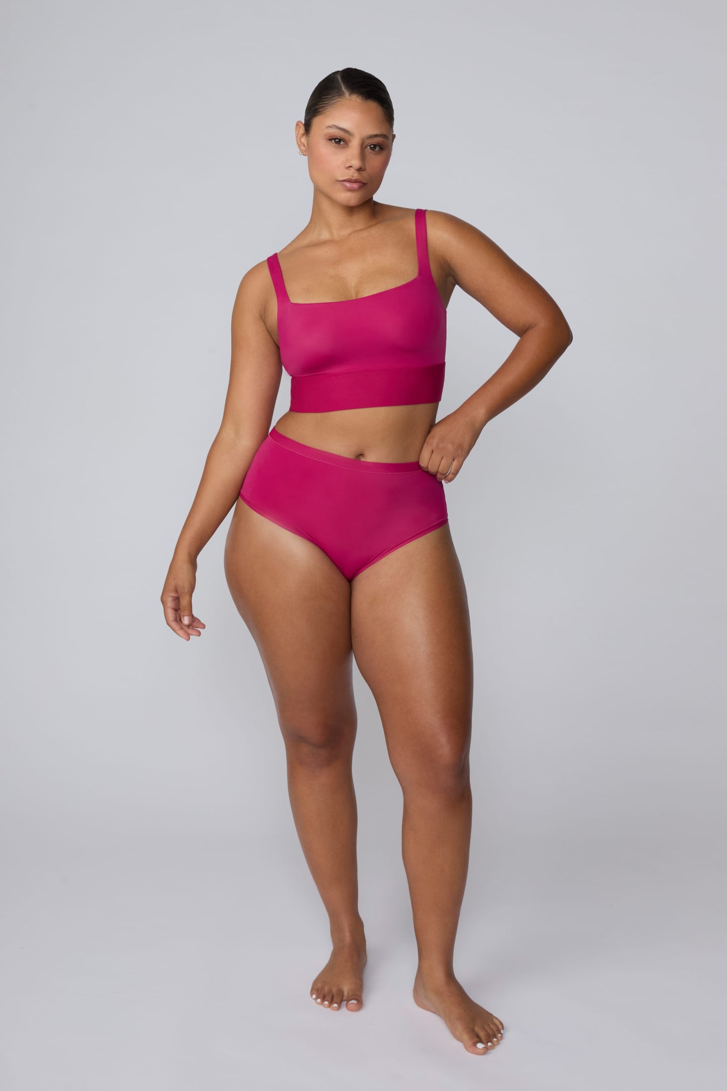 In a studio setting, India wears the Bliss Square Neck Bralette in Winterberry with matching underwear. The full-body front view highlights the square neckline, wide straps, smooth fabric, and wide underband.