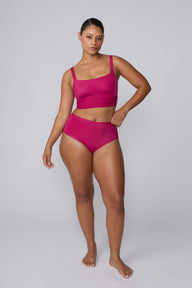 In a studio setting, India wears the Bliss Square Neck Bralette in Winterberry with matching underwear. The full-body front view highlights the square neckline, wide straps, smooth fabric, and wide underband.