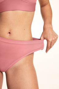 Close-up of model pulling the waistband of the Bliss Thong in Cinnamon to show stretch
