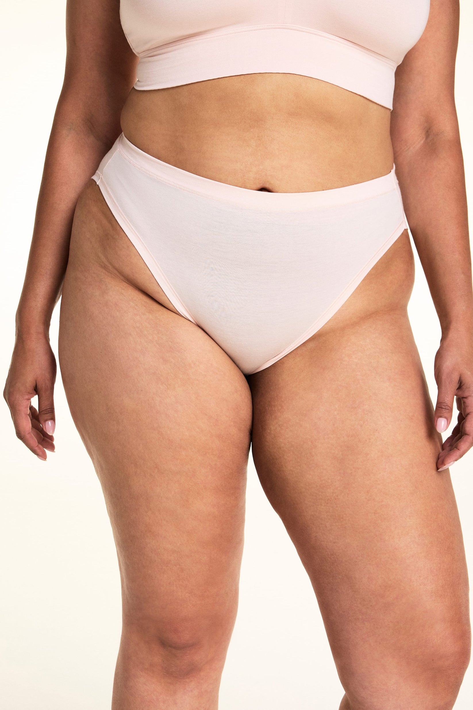 On a light studio backdrop, Jennifer wears the Cloud Cotton French Cut in Dogwood. The close-up highlights the smooth waistband, high-cut leg opening, and soft cotton fabric.