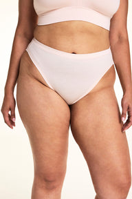 On a light studio backdrop, Jennifer wears the Cloud Cotton French Cut in Dogwood. The close-up highlights the smooth waistband, high-cut leg opening, and soft cotton fabric.