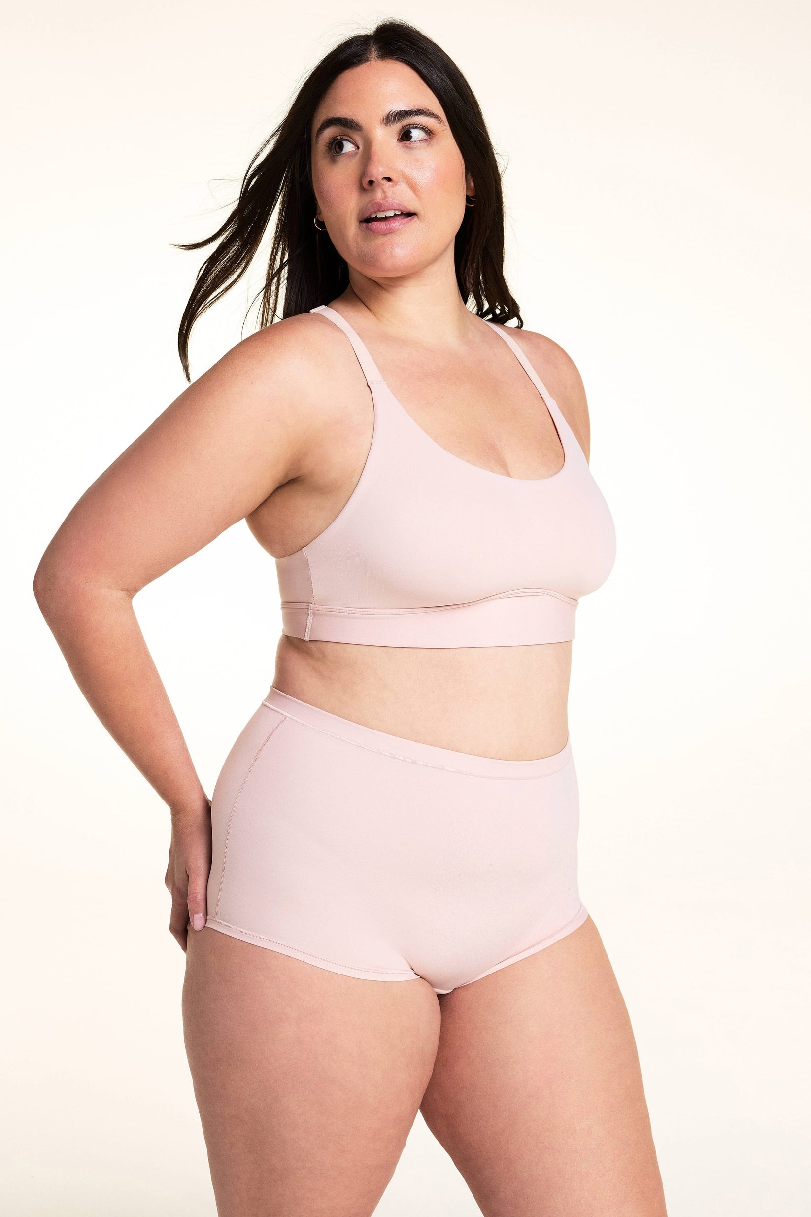 On a light studio backdrop, Alessandra wears the Bliss Boyshort in Ember Rose with the matching bra. The angled image highlights the smooth fabric, mid-rise waist, and full-coverage silhouette.