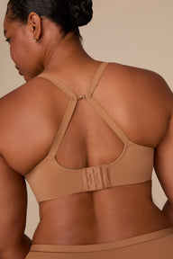 On a neutral beige backdrop, Zarria wears the Base Wirefree T-Shirt Bra in Tan with matching underwear, highlighting the smooth cups, wireless design, and adjustable straps.