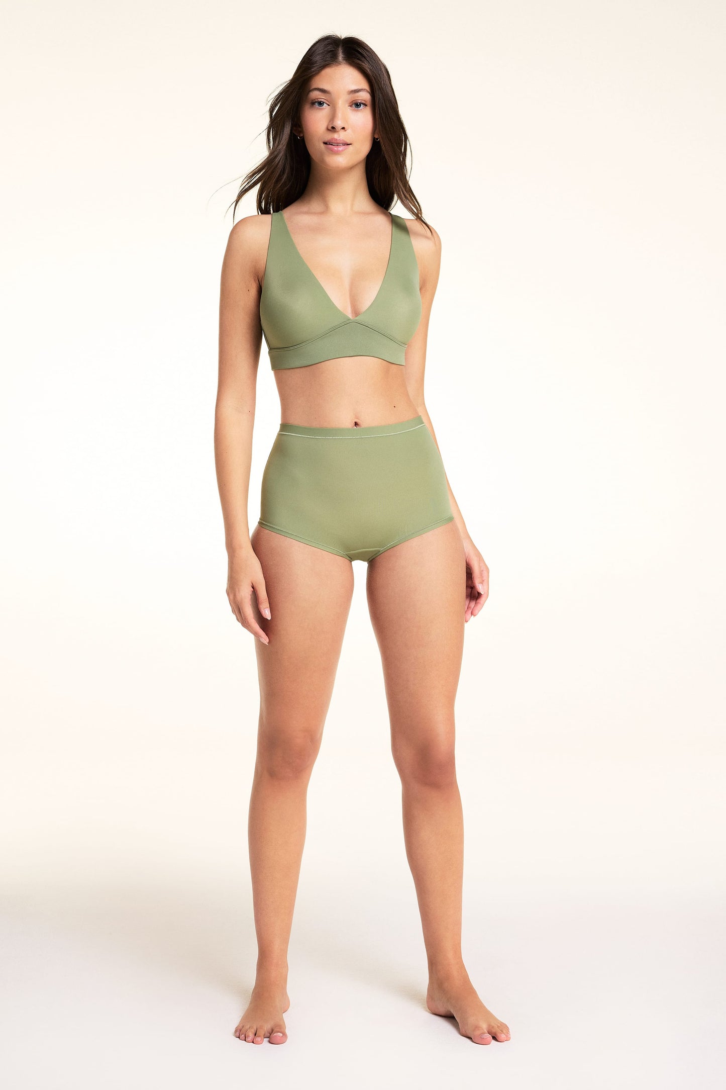 On a white studio backdrop, Laura stands wearing the Bliss Boyshort in Dill with a matching Bliss Triangle Bralette. The full-length view shows the high-rise silhouette and smooth microfiber fabric.
