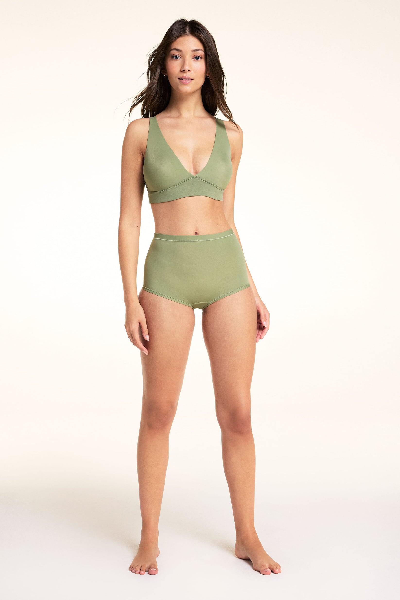 On a white studio backdrop, Laura stands wearing the Bliss Boyshort in Dill with a matching Bliss Triangle Bralette. The full-length view shows the high-rise silhouette and smooth microfiber fabric.