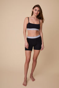 On a neutral studio backdrop, Gracie wears the Cloud Cotton Retro Bandeau Bralette and Cloud Cotton Retro Boxer Brief in Black. She stands with a relaxed smile, highlighting the square-neck bandeau silhouette, thin adjustable straps, and full-coverage boxer brief design in soft cotton modal fabric.