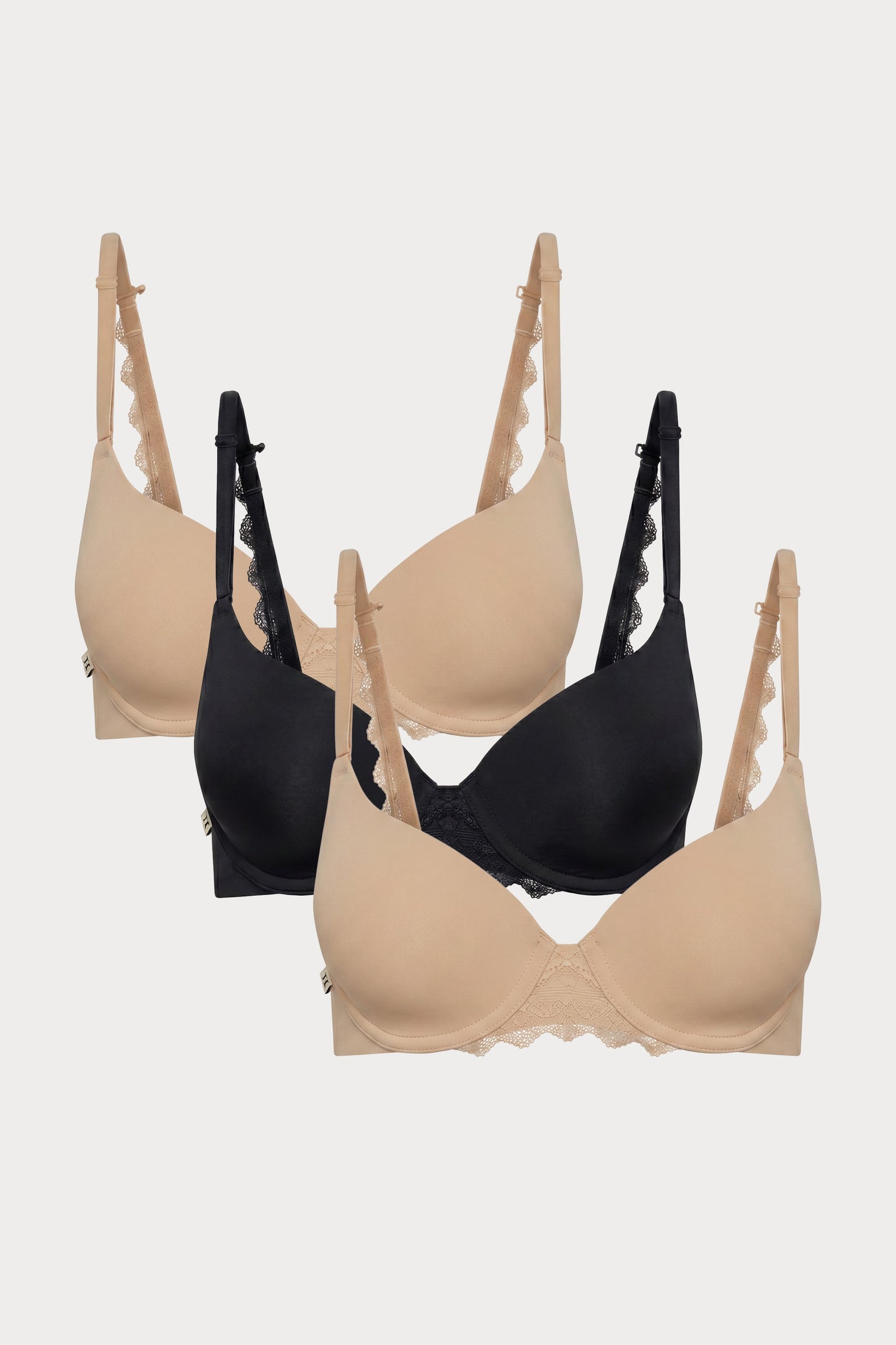 Flat lay image of 3 Base Lace T-Shirt Bras in Beige and Black showcasing the soft lace detail at the center and along the back strap.