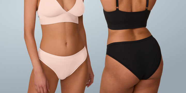 Two models wearing matching bralette and underwear sets. From left to right, the models wear the Bliss Plunge Adjustable Bralette and Bliss Bikini in Rose and the Bliss Triangle Bralette and Bliss Bikini in Black. The right model faces away from the camera to show the moderate coverage of the Bikini.