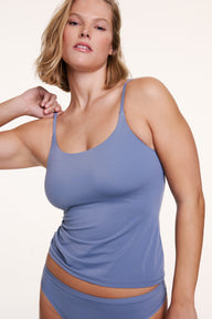 In a studio setting, Sonnie wears the Bliss Apparel Cami in Steel with matching underwear, adjusting the strap to show the thin, adjustable design and soft, flexible fit.