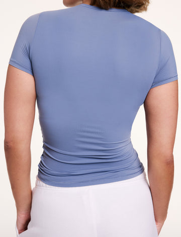 In a studio setting, Sonnie is shown from the back wearing the Bliss Apparel T-Shirt in Steel, featuring short sleeves and a smooth, second-skin fit.