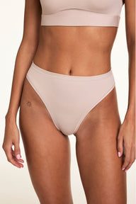On a neutral studio backdrop, Linni wears the Bliss French Cut Brief in Pebble with the Bliss Scoop Adjustable Bralette, showing the high-rise fit, high-cut legs, and smooth microfiber fabric.  sizing: Linni wears size Small
