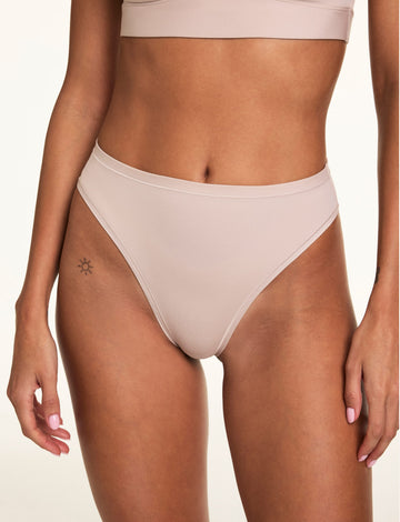 On a neutral studio backdrop, Linni wears the Bliss French Cut Brief in Pebble with the Bliss Scoop Adjustable Bralette, showing the high-rise fit, high-cut legs, and smooth microfiber fabric.  sizing: Linni wears size Small