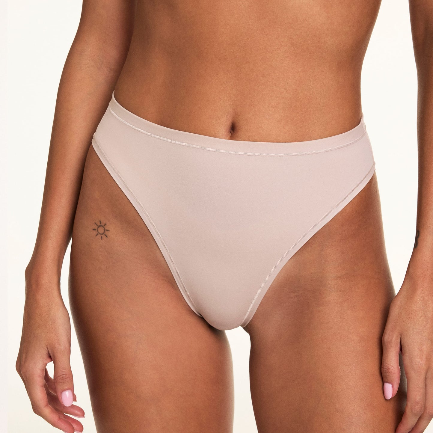In a cropped studio close-up, Linni wears the Bliss French Cut Brief in Pebble, featuring the smooth waistband, high-cut silhouette, and soft microfiber fabric.