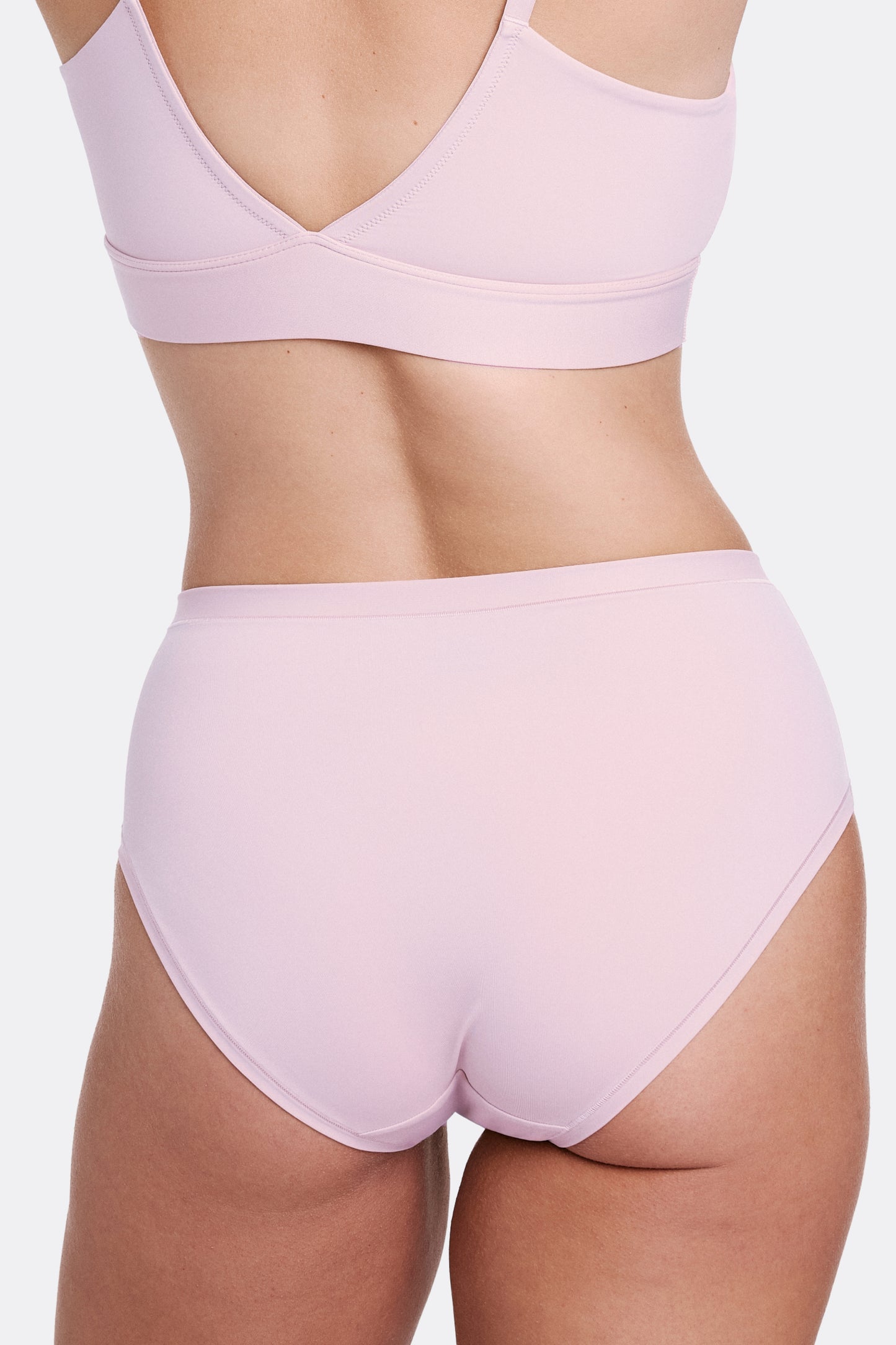 In a studio setting with a neutral backdrop, Sonnie wears the Bliss Triangle Bralette and Bliss Highwaist Brief in Retro Lilac, shown from the back. The underwear features a high-rise silhouette, full coverage, and ultra-soft microfiber fabric for a smooth, comfortable feel.
