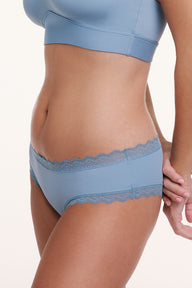 In a white studio setting, Sonnie wears the Bliss Lace Cheeky in Poolside, shown in a close-up side view highlighting the soft microfiber fabric and scalloped lace trim along the waistband and leg openings. sizing: Sonnie wears size Large