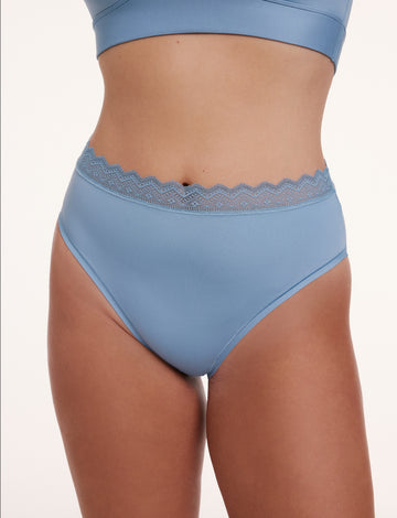 In a studio setting with a neutral backdrop, Sonnie wears the Bliss Lace High Waist Brief in Poolside blue in a front view. The brief features a flattering high-rise fit, soft microfiber body, and scalloped lace waistband for a smooth, comfortable feel.  sizing: Sonnie wears size Large