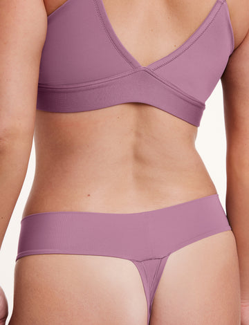 In a studio setting, a model wears the Bliss Low Rise Thong in Mirage with a matching bra, shown from the front. The thong features a low-rise fit, minimal coverage, and a smooth, seamless construction.