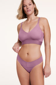 In a studio setting, a model wears the Bliss Low Rise Thong in Mirage with a matching bra, shown in a front-facing pose. The thong features a low-rise fit, minimal coverage, and smooth, seamless fabric.