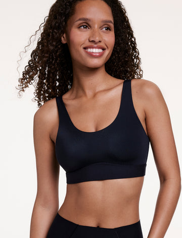 In a studio setting, Courtney wears the Bliss Scoop Bralette in Black, featuring a scoop neckline, wireless lift, and soft microfiber fabric for lightweight, everyday comfort. sizing: Courtney wears size Small