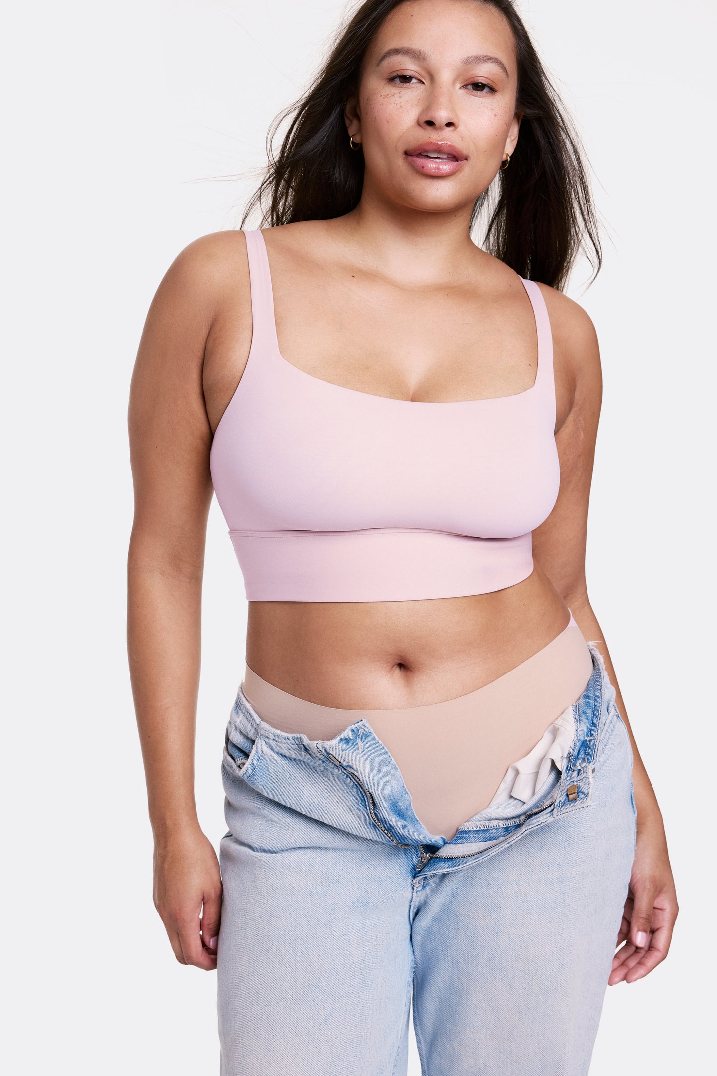 In a studio setting with a light gray backdrop, Alana wears the Bliss Square Neck Bralette in Retro Lilac with matching underwear and relaxed denim, featuring a square neckline and longline silhouette. The bralette has thin adjustable straps and a soft wireless band, made from smooth microfiber fabric for comfortable support. sizing: Alana wears size Large