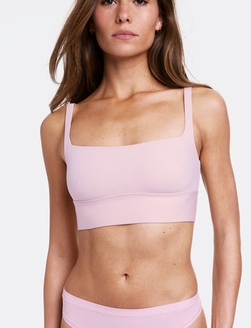 In a studio setting with a light gray backdrop, Gianna wears the Bliss Square Neck Bralette in Retro Lilac with matching underwear, featuring a square neckline and a longline silhouette. The bralette has thin adjustable straps and a soft wireless band for comfortable support, made from smooth microfiber fabric.  sizing: Gianna wears size Small
