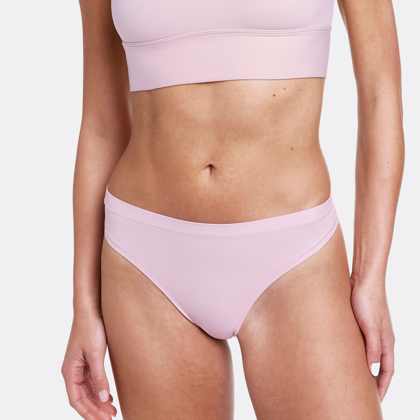 In a studio setting with a neutral backdrop, Gianna wears the Bliss Thong in Retro Lilac in a front close-up view. The thong features ultra-soft microfiber fabric, an elastic-free design, and a smooth, low-rise fit.