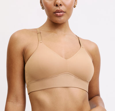 Model wearing the Harper Wilde Bliss Triangle Bralette in Tan — wire-free triangle bralette with V-neckline, adjustable straps, and smooth microfiber cups. Sizes large and above have a higher rise in the front for more support.