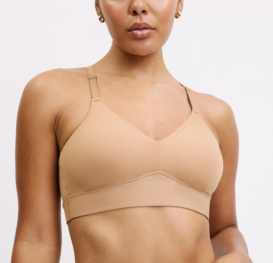 Model wearing the Harper Wilde Bliss Triangle Bralette in Tan — wire-free triangle bralette with V-neckline, adjustable straps, and smooth microfiber cups. Sizes large and above have a higher rise in the front for more support.