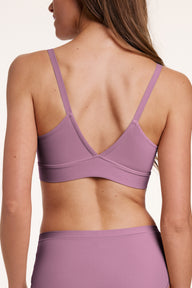 In a studio setting, Gianna wears the Bliss Triangle Bralette in Mirage, shown from the back with adjustable straps and a smooth, wide underband that sits comfortably across the back.