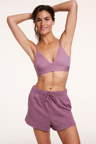 In a studio setting, Gianna wears the Bliss Triangle Bralette in Mirage paired with matching lounge shorts. The bralette features wireless cups, a deep V neckline, and a wide underband for lightweight support. sizing: Gianna wears size Small