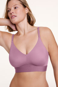 In a studio setting, Sonnie wears the Bliss Triangle Bralette in Mirage, shown in a close-up with a deep V neckline, wireless cups, and a wide underband. The soft fabric and adjustable straps provide lightweight support. sizing: Sonnie wears size XL