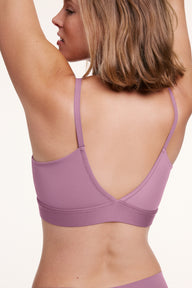 In a studio setting, Sonnie wears the Bliss Triangle Bralette in Mirage, shown from the back with adjustable straps and a smooth, wide underband that sits comfortably across the back.