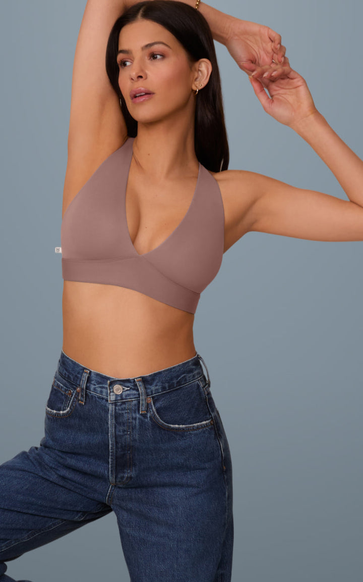 Two models wearing the Harper Wilde Bliss Plunge Adjustable Bralette, one in Mauve and one in Frost, posing side-by-side against a blue background, showcasing color variety and plunge neckline.