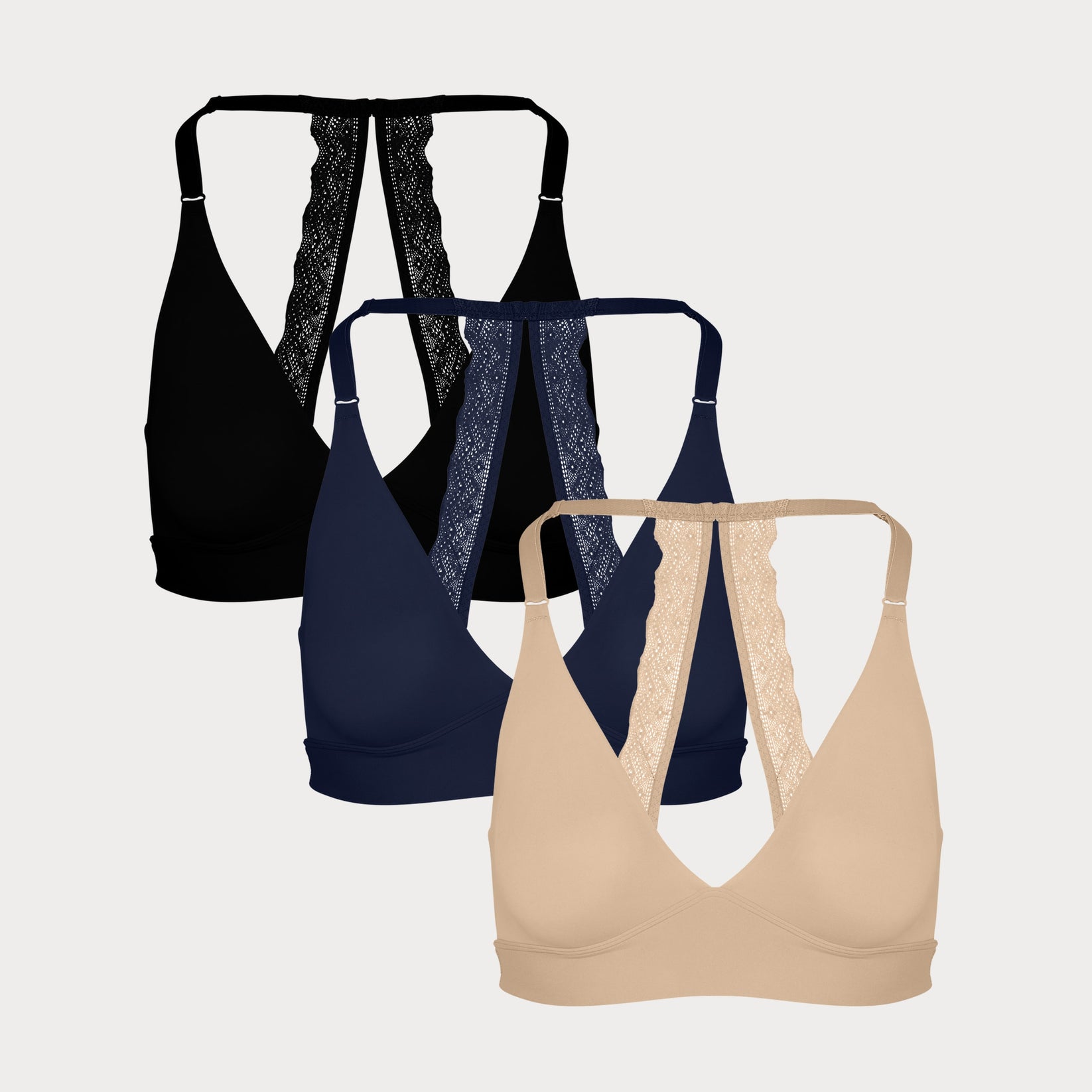 Three Bliss Lace Halterneck Bralettes in Black, Navy, and Beige displayed on a light grey background, highlighting the signature lace back detail.