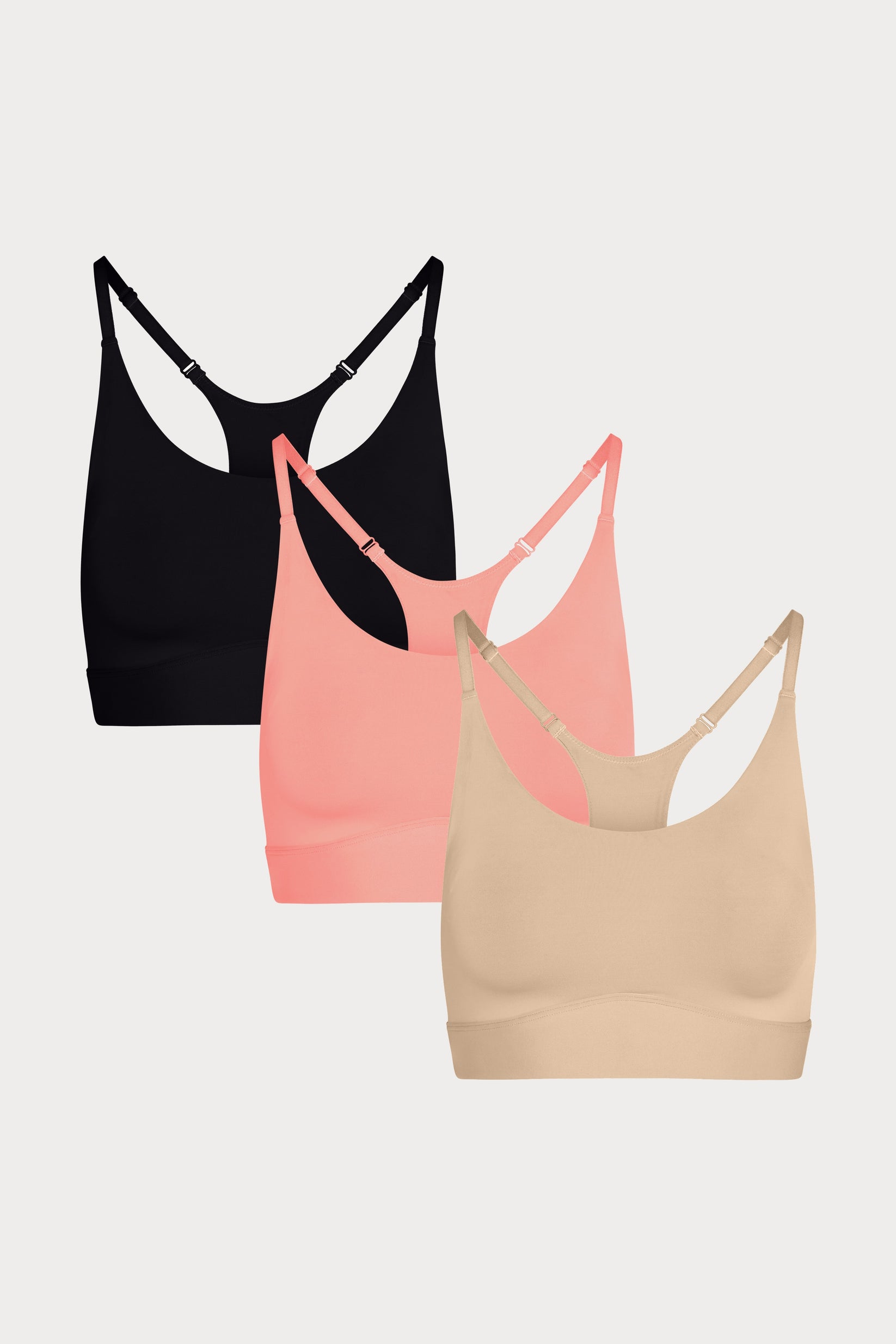 Three Bliss Racerback Bralettes in Black, Cabana, and Beige displayed on a light grey background, showing the adjustable racerback straps.
