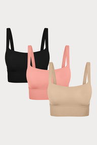 Three Bliss Squareneck Bralettes in Black, Cabana, and Beige displayed on a light grey background, showing the wide square neckline and thick shoulder straps.