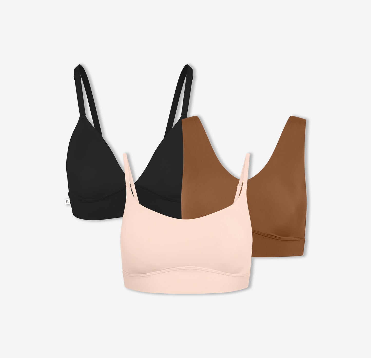 A trio of Harper Wilde's Bliss Triangle Bralette in Black, Bliss Bralette in Brown, and Bliss Scoop Bralette in Rose which offers ultra-soft wireless support and comfort.