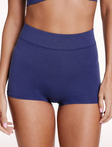 On a white studio backdrop, Linni wears the Cloud Cotton Boyshort in Desert Shadow, shown from the front. The boyshort features a high-rise waistband and full coverage in soft cotton modal fabric. sizing: Linni wears size Small