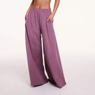 In a studio setting, Courtney wears Cloud Cotton pants in Mirage, showing the elastic waistband, side pockets, and relaxed wide-leg silhouette in soft, drapey fabric.
