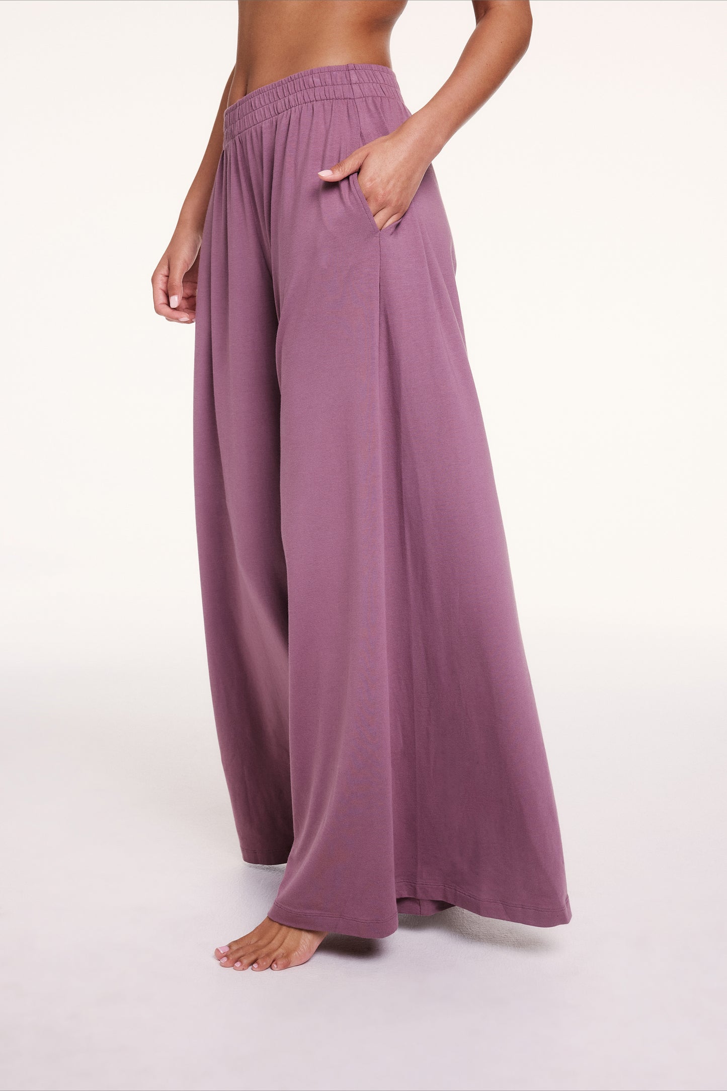 In a studio setting, Courtney wears the Cloud Cotton pants in Mirage, showing the elastic waistband and side pockets, with soft, drapey fabric falling into a wide-leg silhouette. sizing: Courtney wears size Small