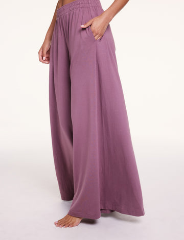 In a studio setting, Courtney wears the Cloud Cotton pants in Mirage, showing the elastic waistband and side pockets, with soft, drapey fabric falling into a wide-leg silhouette. sizing: Courtney wears size Small