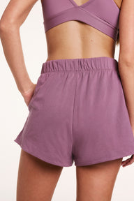 In a studio setting, Gianna wears Cloud Cotton shorts in Mirage, shown from the back with an elastic waistband and relaxed fit in soft, breathable fabric.