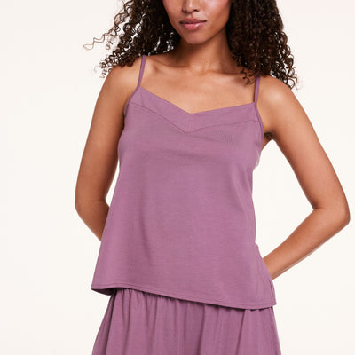 In a studio setting, Courtney wears the Cloud Cotton tank in Mirage, highlighting the soft V-neckline, thin straps, and smooth, drapey fabric.