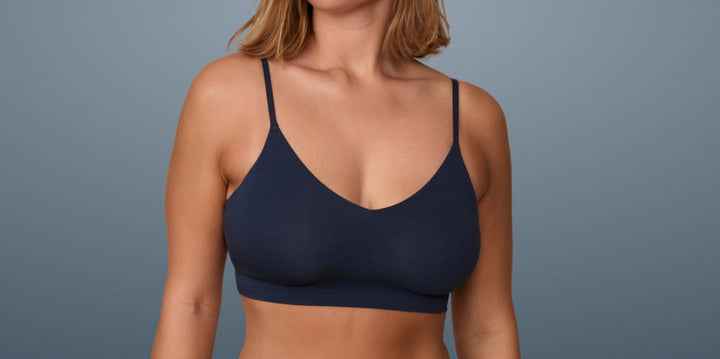 Woman wearing Cloud Cotton Triangle Bralette in Midnight, shown against a blue background.